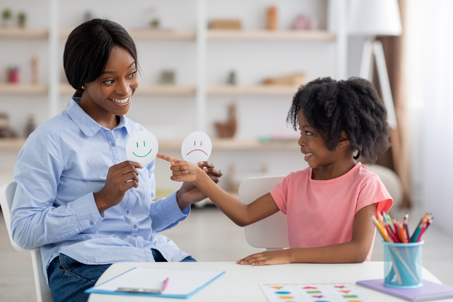 black female teacher with black female student practicing emotions sad and happy