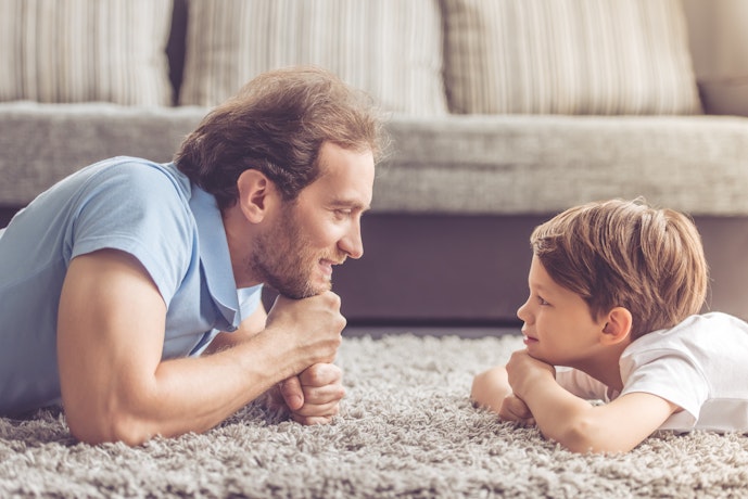Father and young son lying on the floor face to face having a conversation