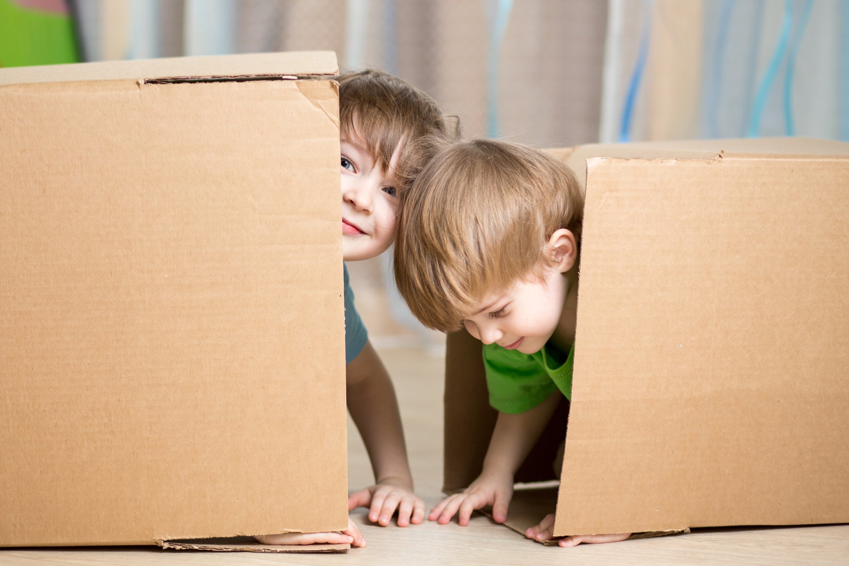 Two young boys using boxes for play-based learning
