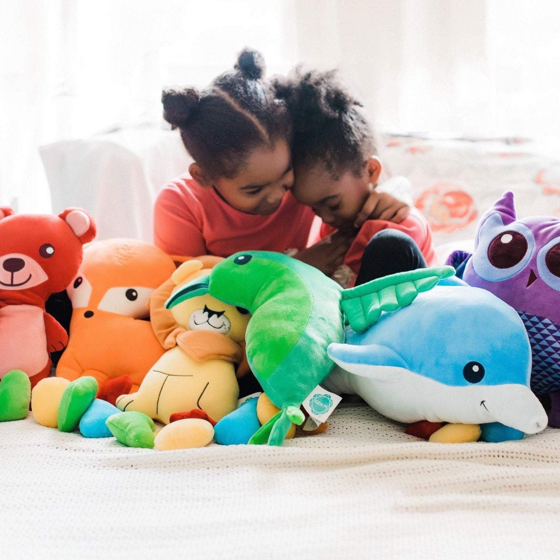 two young children snuggling beside a row of colorful emotions plush stuffed animals